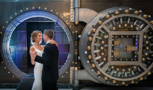 Couple dancing in front of a large open bank safe.