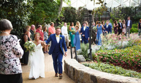 Bride and groom holding hands while walking back up the isle after their ceremony in The Domes.