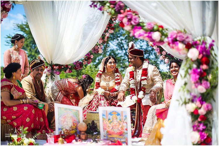 Bride and groom smiling at each other during an Indian wedding ceremony.