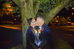 Happy Couple Kissing Under Tree at Wedding
