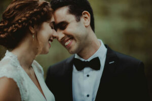 Bride and groom smiling while pressing their foreheads together at Boerner Botanical Gardens