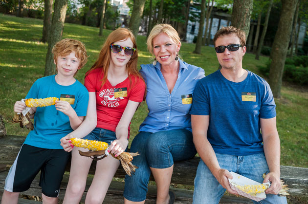 Family eating corn at a tailgate event