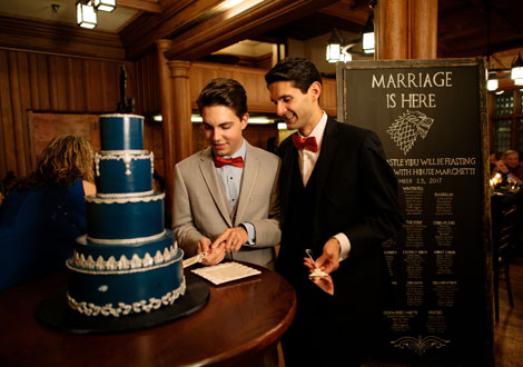 Groom and groom cutting a dark blue wedding cake.