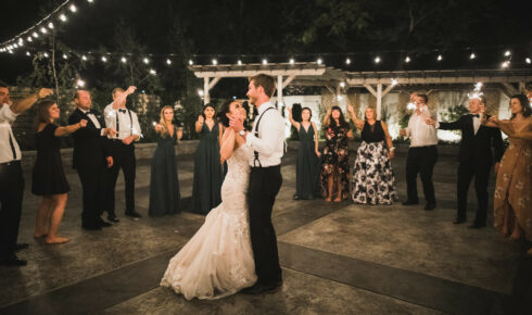 Couple dancing on patio as guests surround at night.