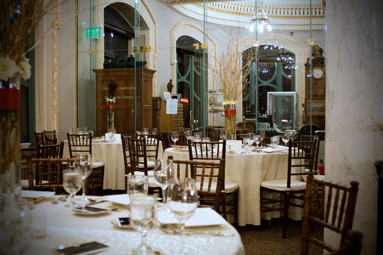 Tables set for a holiday party with white linens.