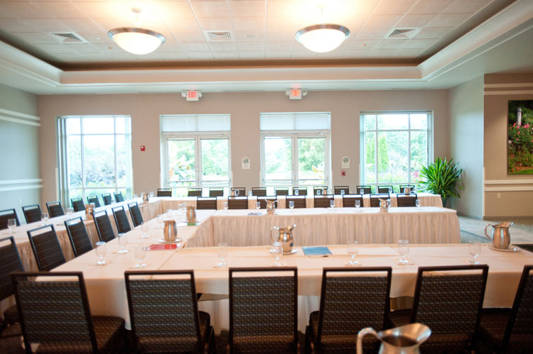 Dining tables set with white linens and black chairs.