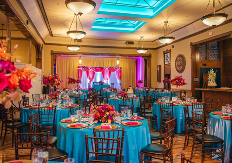 Reception tables set with blue table cloths and pink napkins.