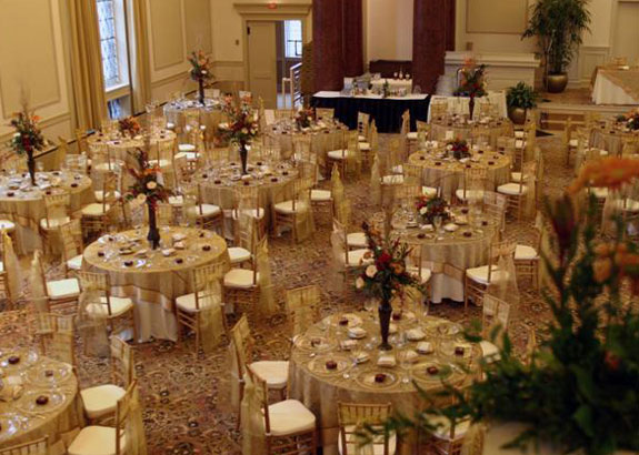 Reception tables set with gold and pops of dark red.
