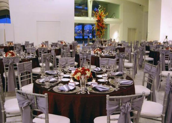 Tables set with dark red linens and grey napkins.