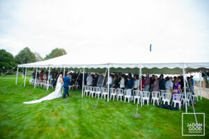 Bride walking into a party tent while the guests stand.