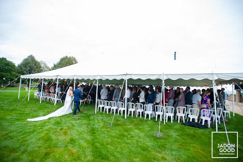 Bride walking into a party tent while the guests stand.