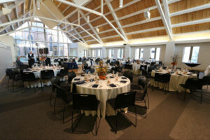 Tables set with white linens, black tables and chairs, and fall colored floral arrangements at The Grace Center.