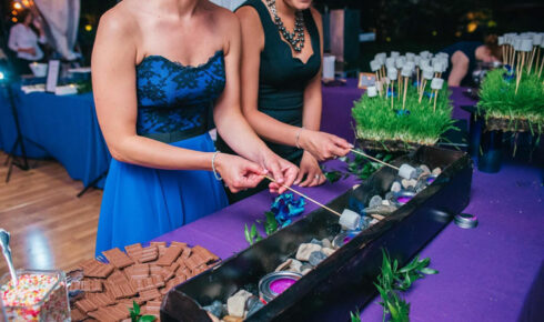 Two wedding guests roasting marshmallows at a smores station.