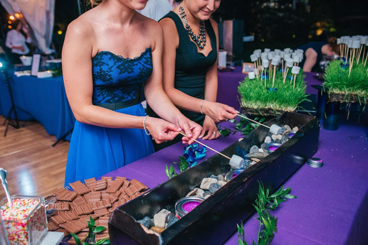 Two wedding guests roasting marshmallows at a smores station.