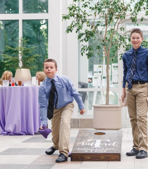 Two boys in blue shirts playing corn hole.