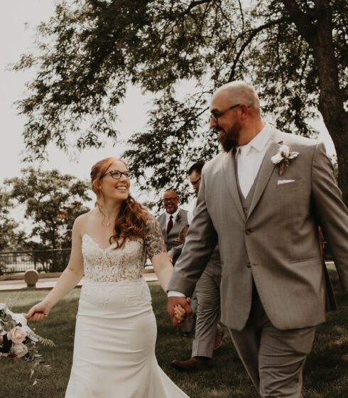 Bride and groom holding hands and looking into each others eyes while walking toward the camera.