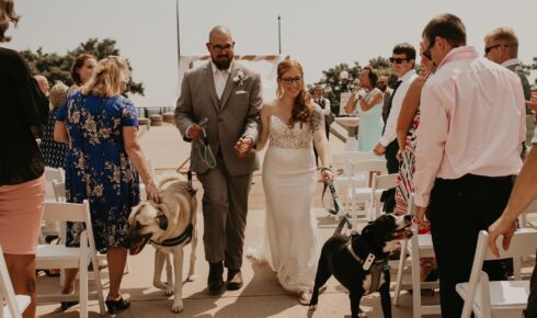 Bride and groom walking back up the isle with their dogs after their ceremony.