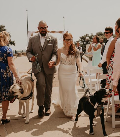 Bride and groom walking back up the isle with their dogs after their ceremony.