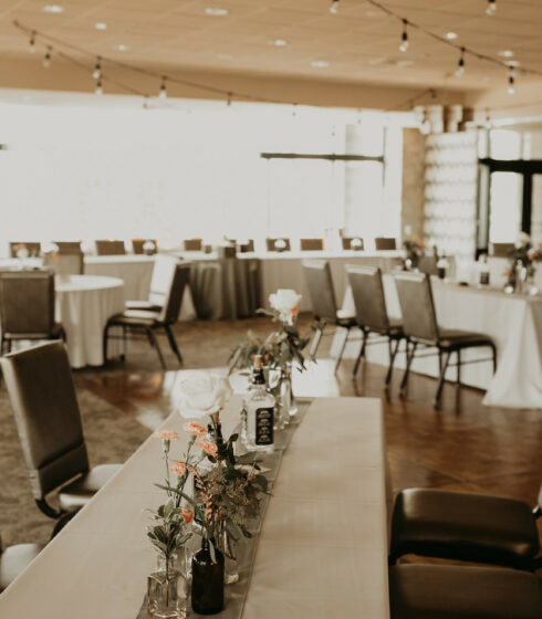 Reception tables set up with table runners, flowers, and glass bottles.