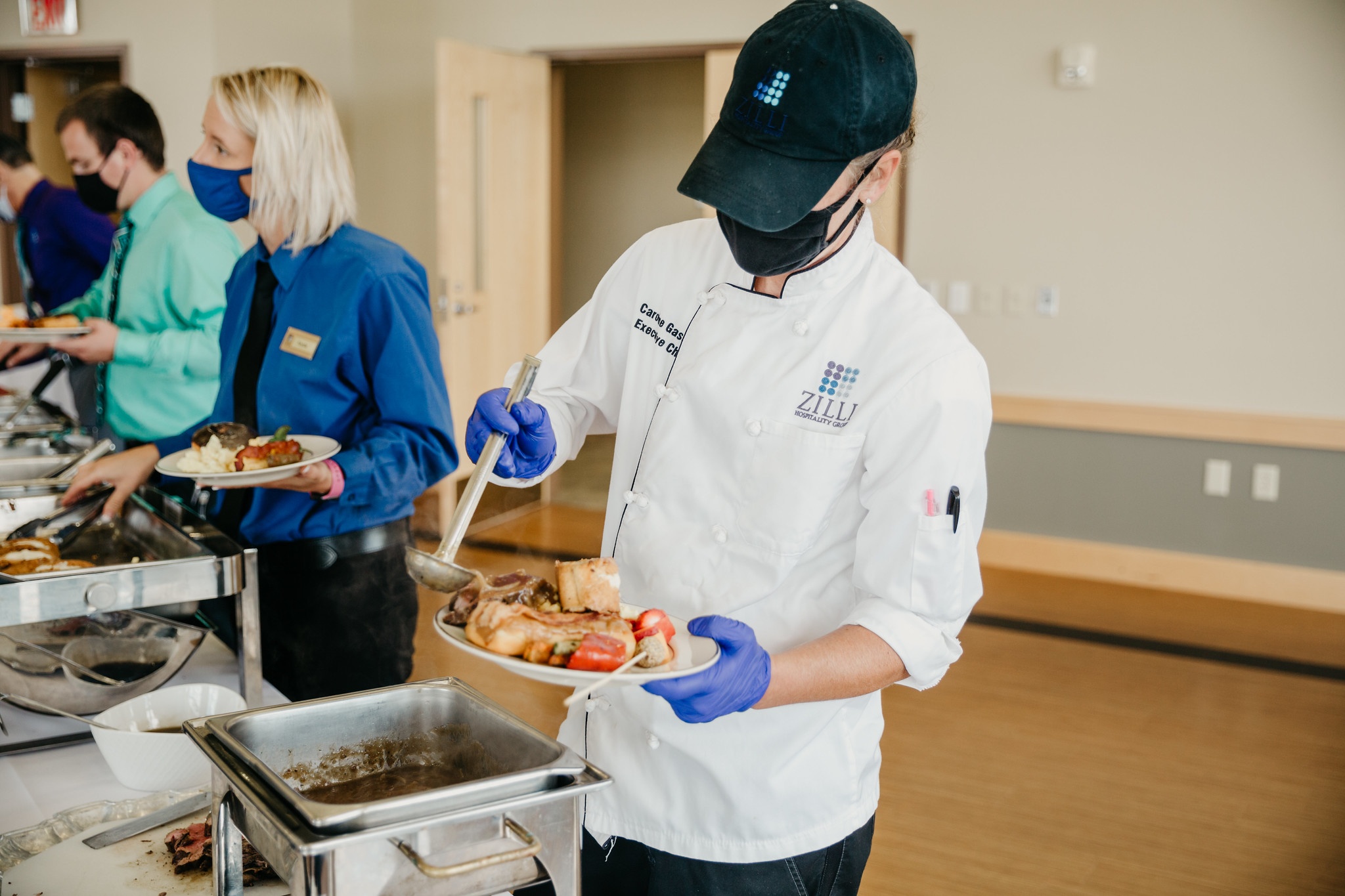 Chef pouring gravy on a plate of food they are serving.
