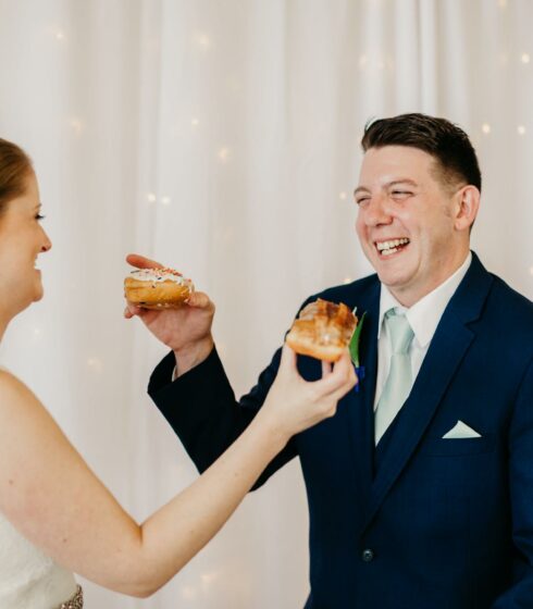 Bride and groom feeding each other donuts.