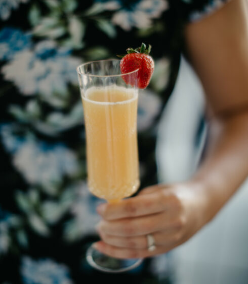 A woman wearing a floral dress holding a mimosa.