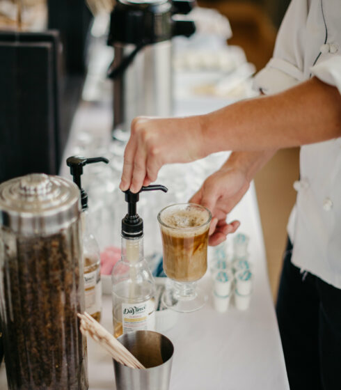 A chef adding flavoring to a latte.