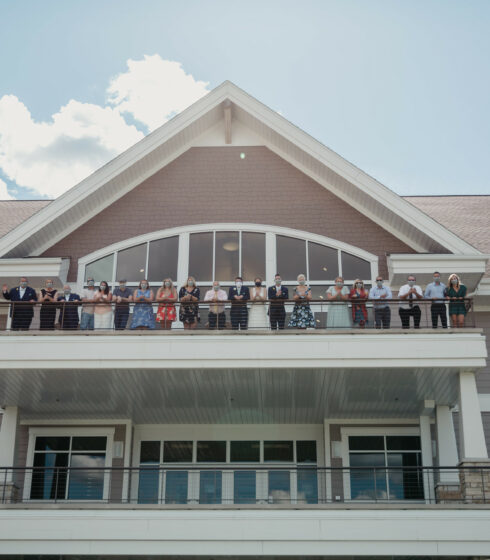 Bride, groom, and family standing on the outdoor balcony at The Oconomowoc Community Center.