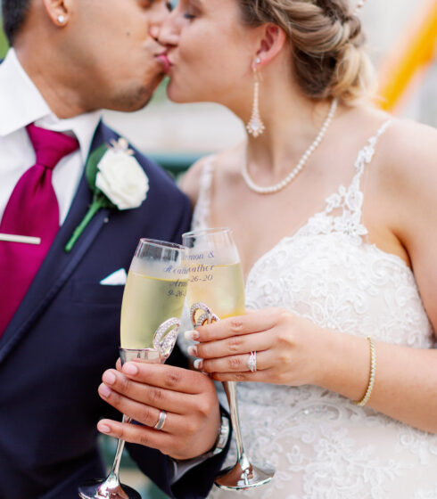 Bride and groom kiss while toasting champagne.