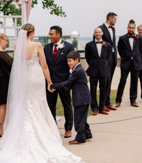 Bride and groom at the alter with a young boy holding their hands during an outdoor ceremony at Zilli Lake and Gardens.