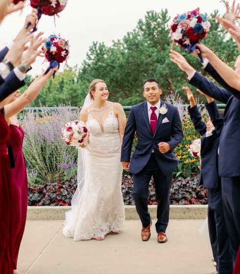 Bride and groom holding hands while walking through a tunnel made by their wedding party.