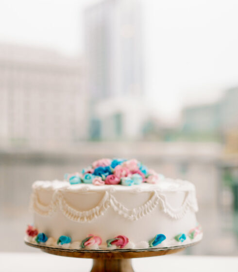 Single layer cake with white frosting and blue, pink, and red flowers.