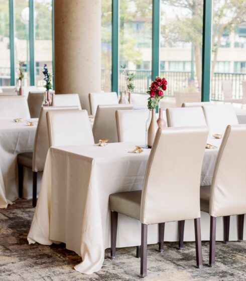 Tables set with wedding decor, white chairs, and white linens at Zilli Lake and Gardens.