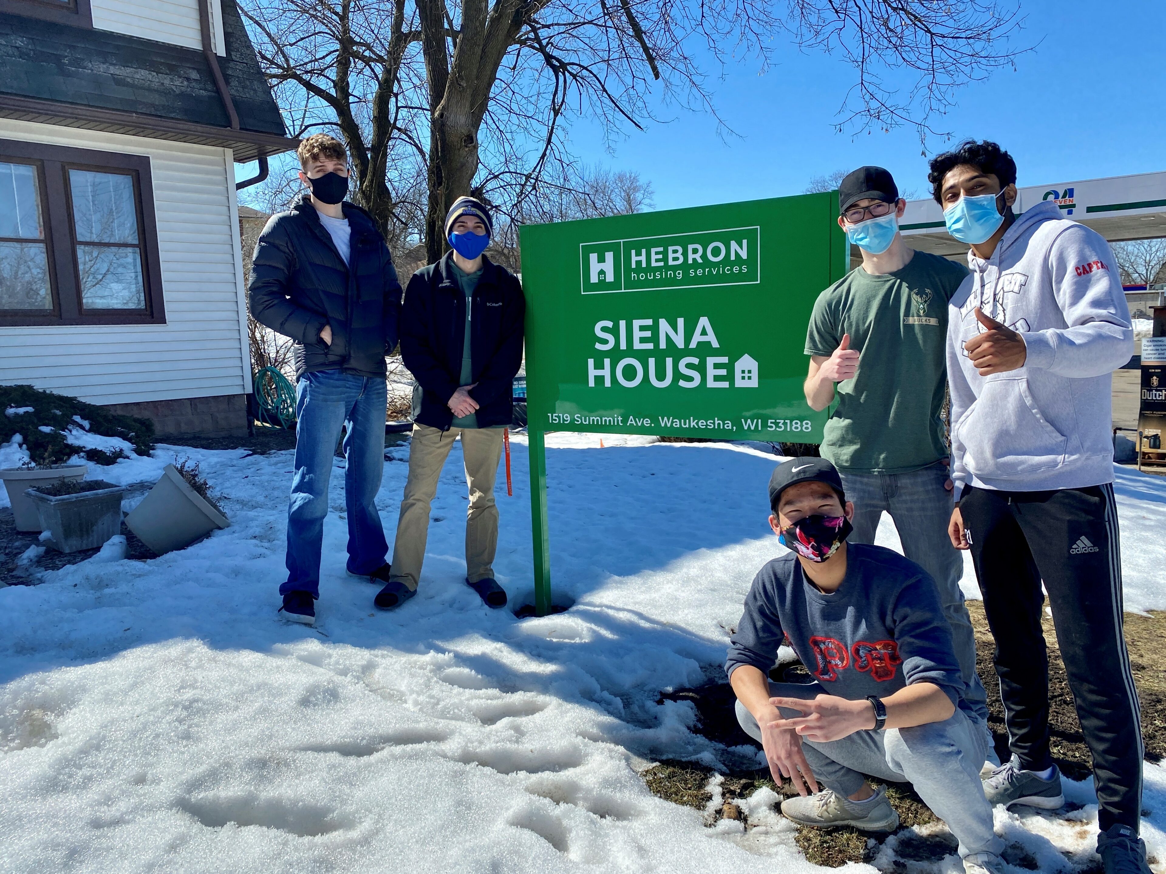 5 people posing by Herbon housing services sign