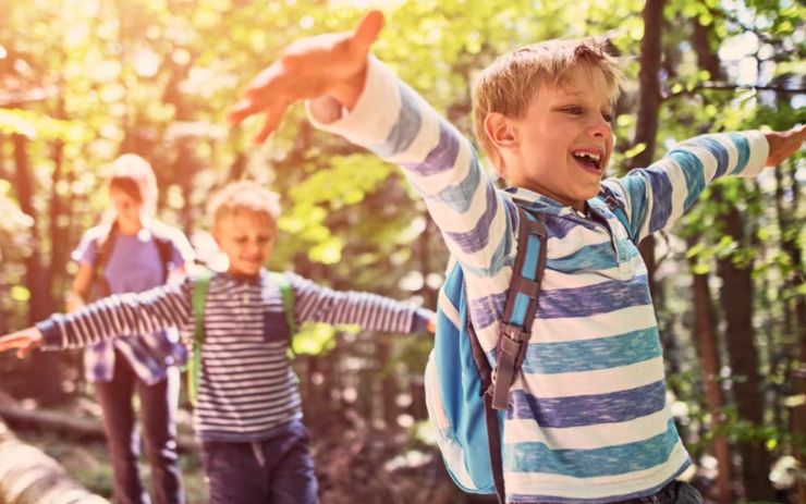 Two boys smiling and walking through the trees