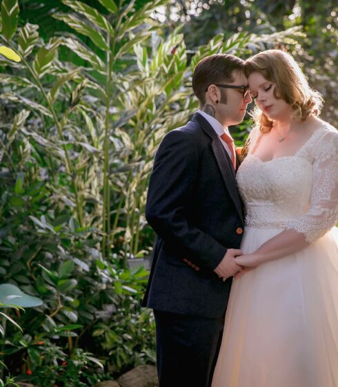 wedding couple in front of green plant background