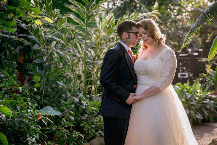 wedding couple in front of green plant background