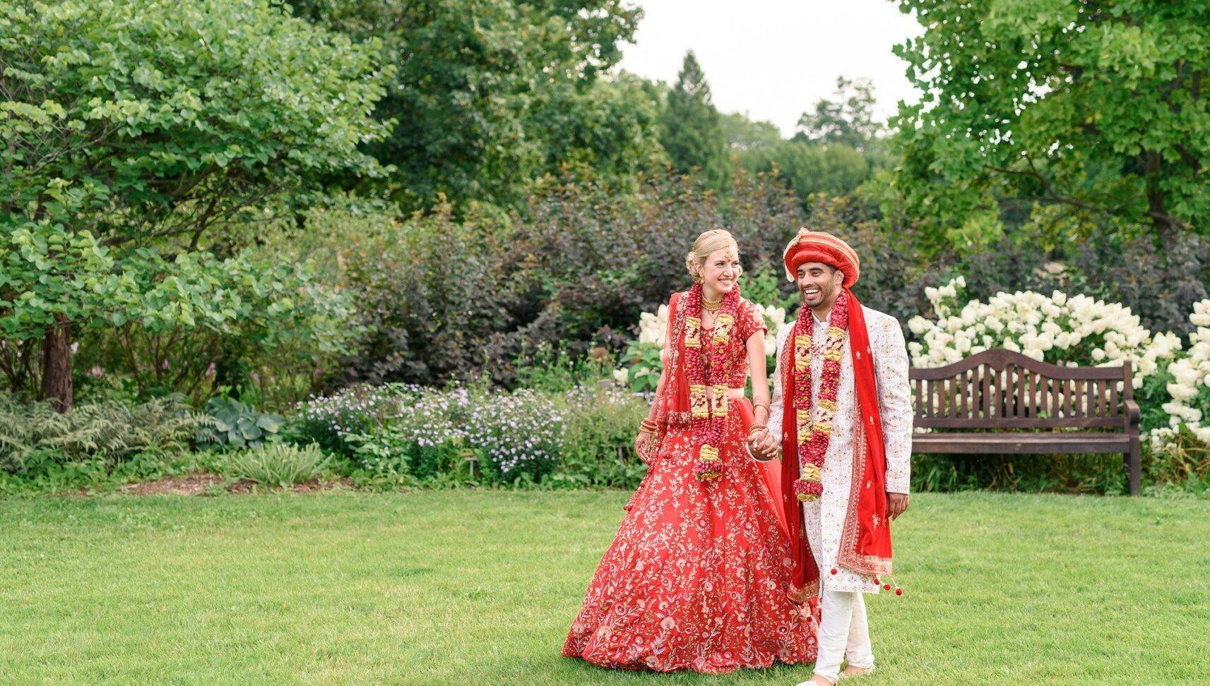 couple walking outside dressed in Indian wedding attire