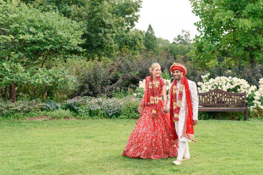 couple walking outside dressed in Indian wedding attire