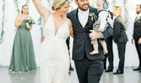 couple walking down aisle with their baby son.