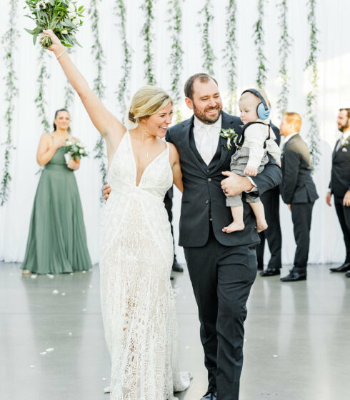 couple walking down aisle with their baby son.