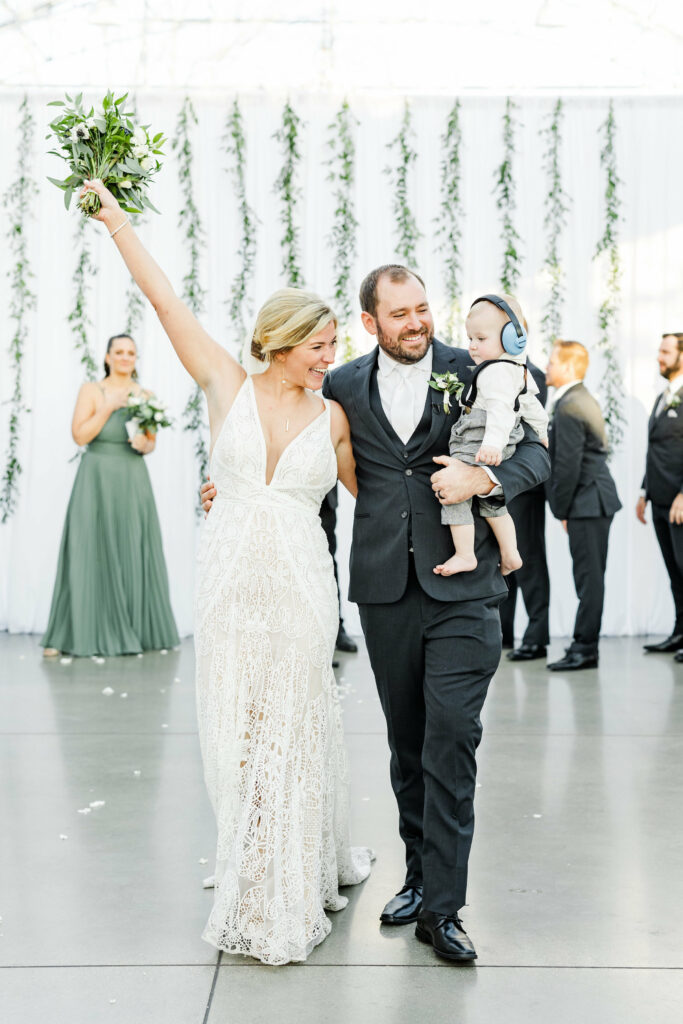 couple walking down aisle with their baby son.