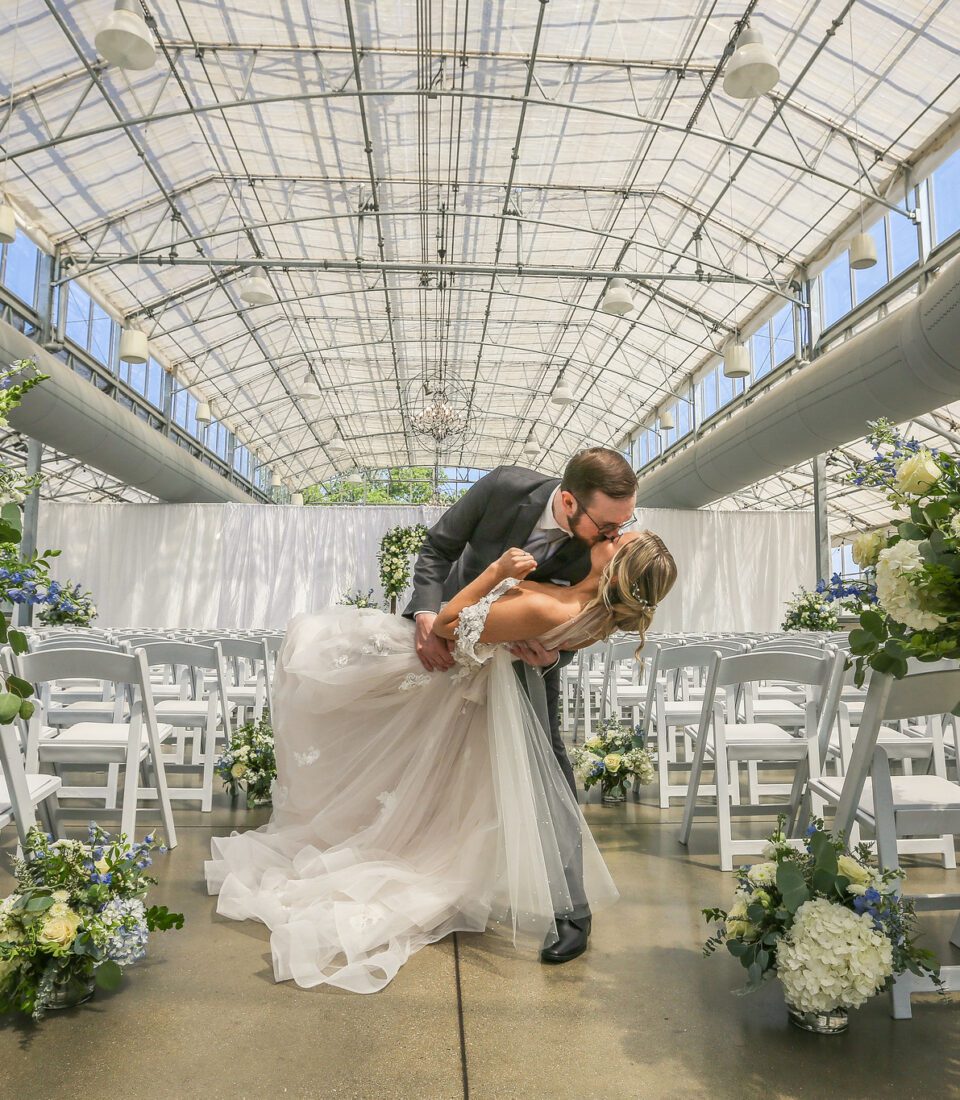 Groom dipping bride under glass dome