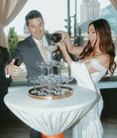 bride and groom standing at table pouring champagne into glasses