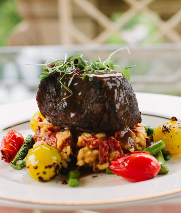 close up of a plate of steak on top of a mix of cooked vegetables